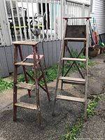 Two wooden ladders standing side by side on driveway