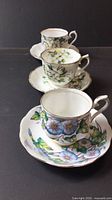 Three Royal Albert cup and saucer sets displayed in a row