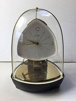 Front view of Kundo Electronic brass pendulum clock under glass dome