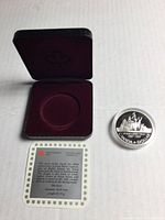 Open clamshell case, coin in capsule, certificate