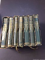 Spines of all seven Collins Olive Classics volumes in slipcases