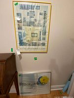 Both framed posters leaning against wall