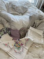 Overview of duvet, pillow sham, sheets, assorted table linens on bed