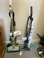 Both Bissell vacuums standing side by side with manuals