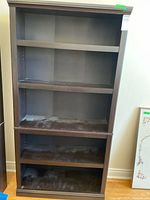 Full front view of tall dark brown bookshelf with four shelf levels