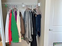 Clothing on closet rod showing variety of sweaters, blouses and jeans