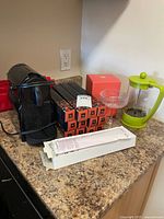 Group shot of Nespresso machine, pod boxes, descaler, glass dish, Bodum press