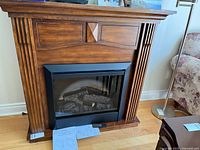 Front view of Dimplex fireplace and mantle, remote and manual visible