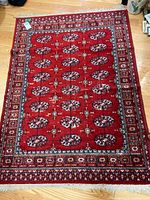 Full view of red Bokhara-pattern wool rug with fringe