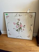 Full view of framed embroidered tablecloth showing central rose bouquet and corner sprays