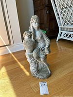 Full view of statue on wood floor with tape showing lot number tag
