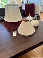 All items group view: lamp bases, one large ivory bell shade, burgundy square shade, small ivory shade