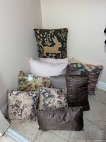 Group of pillows stacked in corner showing variety of patterns and shapes