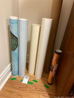Six rolled posters standing vertically showing paper edges and two outer graphics