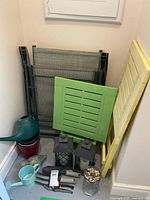 Overall lot showing folded chair, folding tables, lanterns, watering cans, planter, decorative items and tools