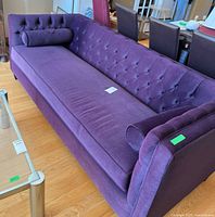 Full view of plum tufted sofa with bolster pillow