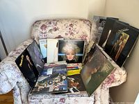 Overview of multiple vinyl records displayed on floral armchair