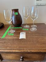 Group shot of four wine glasses and ceramic vase on wooden surface
