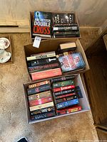Three boxes filled with books, showing variety of hardcover and paperback titles