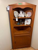 Full front view of corner cabinet showing open shelves and lower cupboard