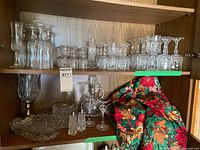 Cabinet shelf with majority of crystal pieces: assorted stemware, decanter, relish dish, vase, shakers