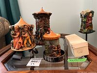 Overview of four carved figural candles on glass surface