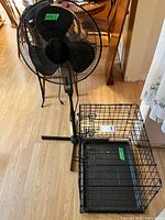 Pedestal fan standing next to folded wire dog crate