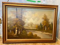 Full view of framed oil painting showing autumn river scene and signature