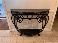 Front view of wrought iron demilune console table with green marble top and shelf