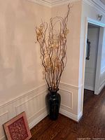 Full view of floor vase with faux arrangement against wall
