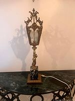 Full view of gilt metal cherub lamp on marble base, cord visible