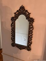 Front view of ornate gold-tone wall mirror hanging on wall