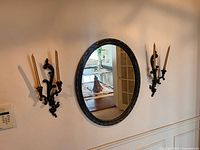 Frontal view of mirror flanked by two sconces on wall