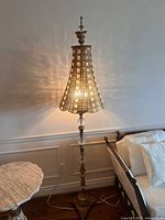 Full view of lamp lit beside bed and side table