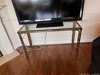 Front view of brass and glass console table beneath television