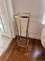 Full view of brass and glass pedestal stand showing overall design