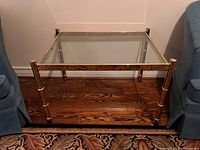 Front view of brass and glass side table between chairs