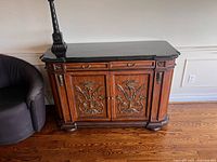 Sideboard angled view showing granite top, drawers, doors, carvings