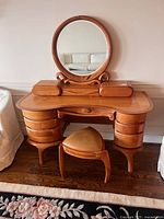 Front view of wooden vanity table, round mirror, stool and drawer layout