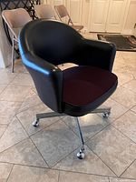 Front angled view of black Nightingale swivel chair with burgundy seat on chrome base with casters