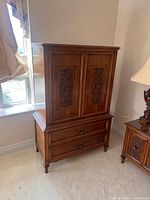 Front view of Peppler's wood armoire showing carved doors and lower drawers