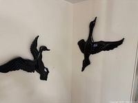 Both bird plaques mounted on wall showing relative size and pose