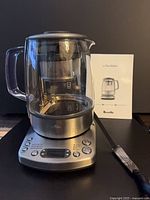 Overall view of glass kettle on powered base with manual visible