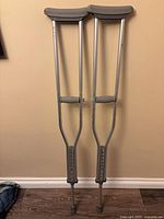 Full view of both aluminum crutches showing pads, grips, tips and adjustment holes