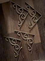Four decorative metal shelf brackets with scroll design