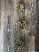 Three metal starburst wall sculptures laid out on floor