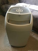 Front three-quarter view of white console humidifier showing grille and overall shape