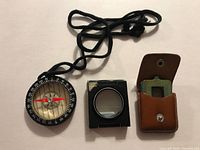 Compass, black loupe, leather pouch shown together