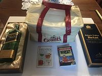 Lot overview showing bottle in box, cooler bag, two books and Blue Label sleeve