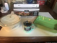 Group shot of casserole with lid, YETI mug, kabob rack box, green baking dish